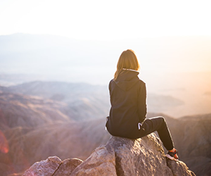 Woman perched atop a rocky outcrop looking at the view