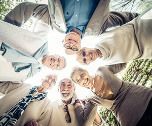 Group of seniors in a circle looking down and smiling